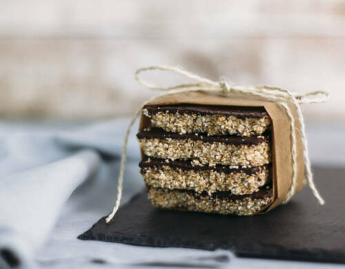 Amaranth-Erdnussbutter-Bars mit Schleife aus Kordel vor hellem Hintergrund.