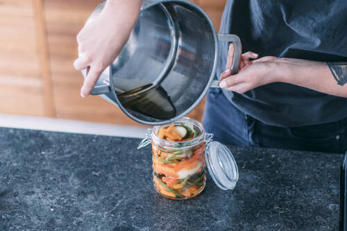 Eingelegtes Gemüse wird mit heißem Essig übergossen