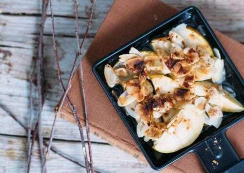 Raclette-Pfännchen mit Äpfeln, Mandelsplittern und Zimt von oben fotografiert.
