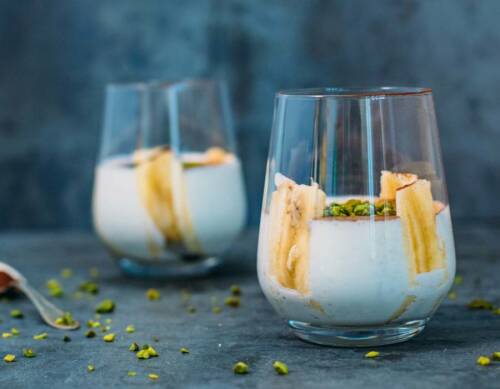 Bananen-Joghurt in Gläsern vor dunklem Hintergrund.