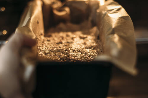 Bananenbrot in Kastenform im Backofen vor dunklem Hintergrund.