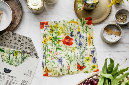 Ein buntes Bienenwachstuch mit dem Motiv "Bienentraum" von Little Bee Fresh auf einem Tisch.