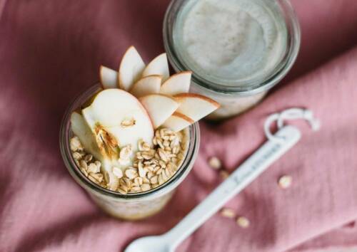Selbst gemachte Bircher-Overnight-Oats in einem Glas mit Apfelscheiben garniert.