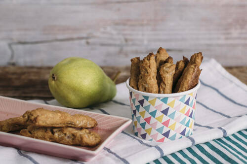 Birnen Dinkelstangen ohne Zucker neben Birne vor hellem Hintergrund.