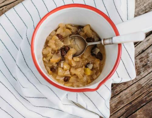Birnen-Rosinen-Chutney in weißer Schüssel mit Löffel vor hellem Hintergrund.