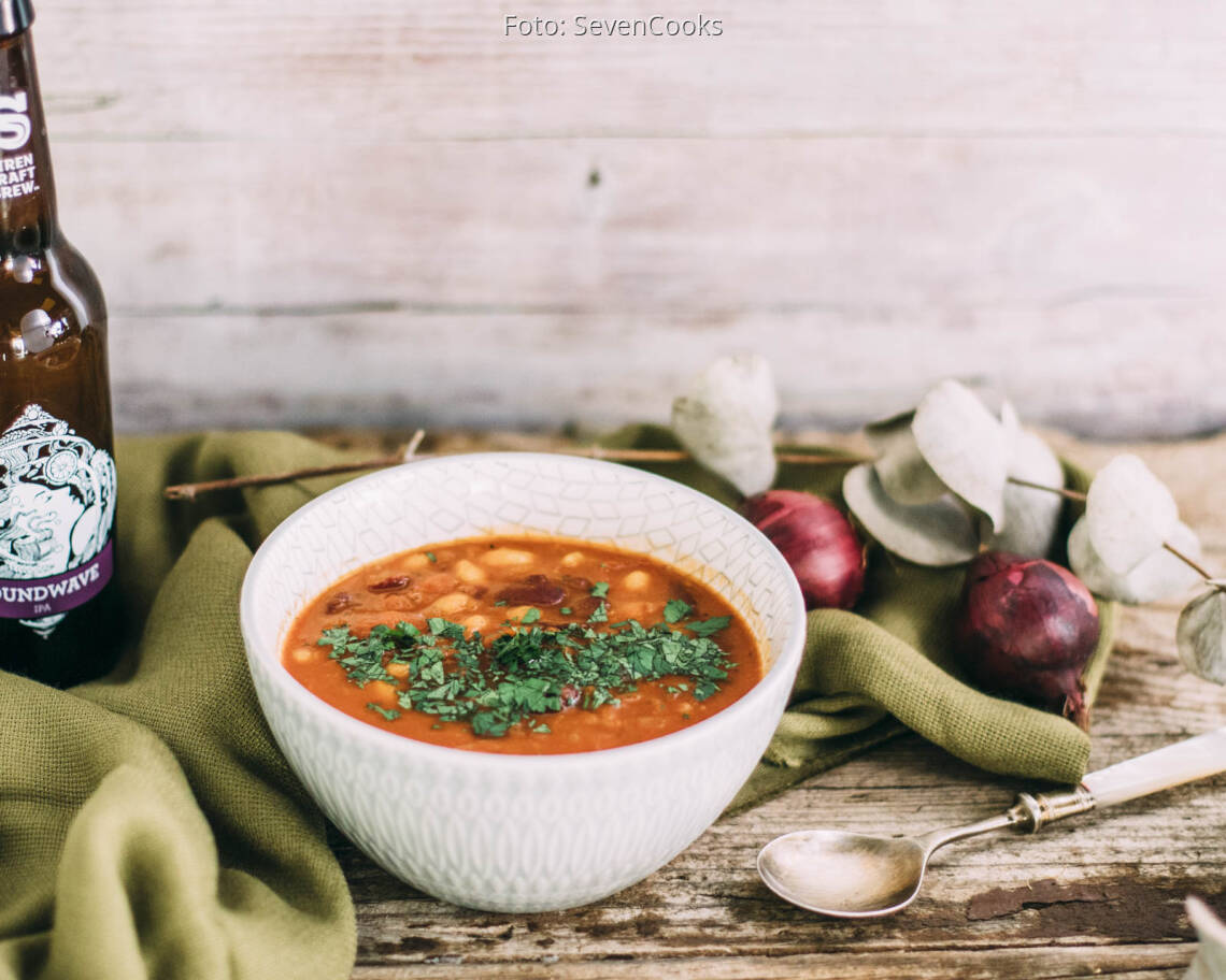 Beschwipste Bohnen dekoriert in einer Schale mit einer Flasche Bier