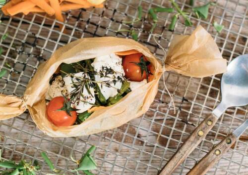 Backpapier-Päckchen mit Gemüse gefüllt auf einem Gitter, von oben fotografiert.