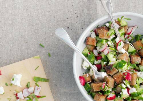Brotsalat in weißer Schüssel vor grauem Hintergrund, von oben fotografiert