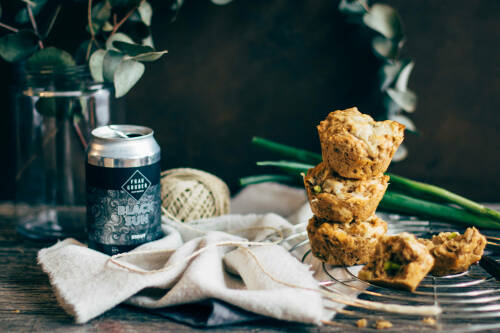 Cheddar Bear Bread Muffins neben Dosenbier und Pflanze vor dunklem Hintergrund.