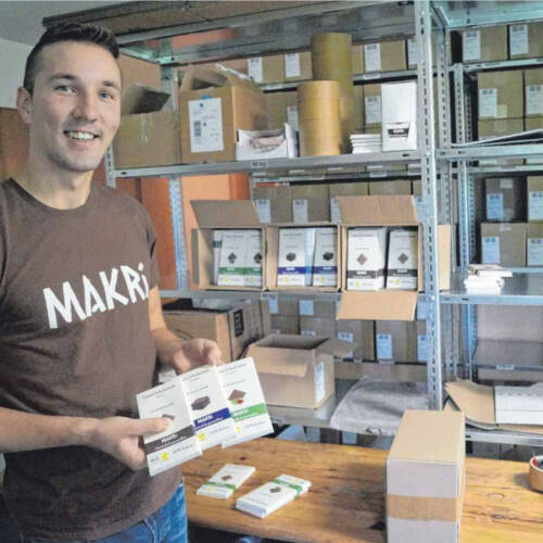 Christian Enderle im Lager von MAKRI mit drei Tafeln in der Hand.