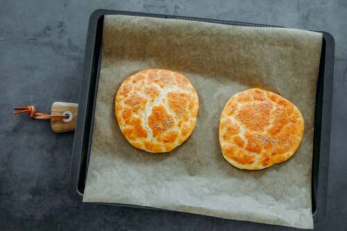 Cloudbread gebacken auf Backblech mit Backpapier vor dunklem Hintergrund.