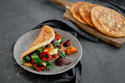 Cloudbread Sandwich mit Grillgemüse auf Teller und Schneidebrett vor dunklem Hintergrund.