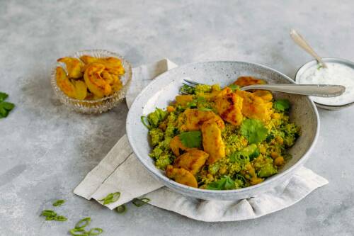Couscoussalat mit Hähnchenstreifen auf weißem Teller mit Gabel vor hellem Hintergrund.