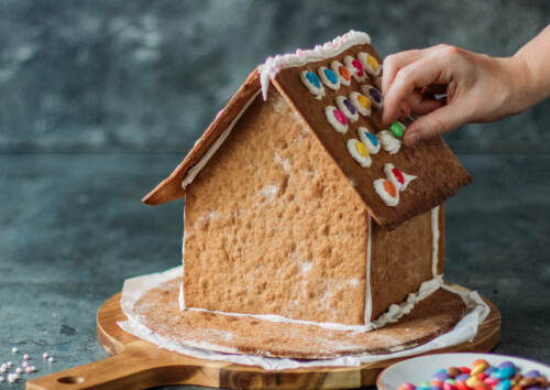 Selbstgemachtes Lebkuchenhaus wird mit Smarties dekoriert.
