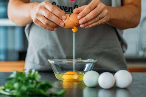 Eier schlagen in Schüssel vor dunklem Hintergrund.