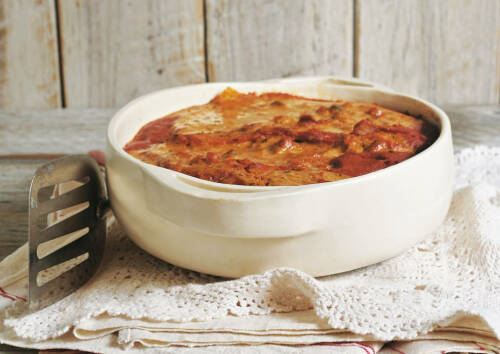 Ein beliebtes mexikanisches Essen sind Enchiladas, diese werden meist überbacken. Hier in einer weißen Schüssel, von vorne fotografiert.