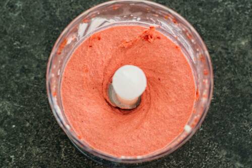 Erdbeereis aus Wasser in Mixer vor dunklem Hintergrund.