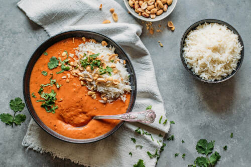 Erdnusssuppe mit Reis in schwarzen Schüsseln vor hellem Hintergrund.