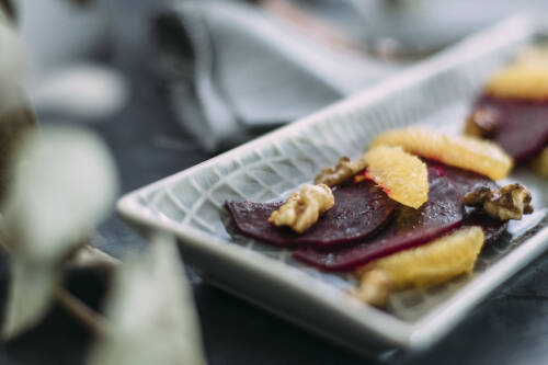 Ein selbst gemachtes Carpaccio aus Rote Bete, Nüssen und Orangenscheiben; in einer grauen länglichen Schale