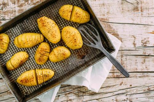 Fächerkartoffeln auf Backblech vor hellem Hintergrund.