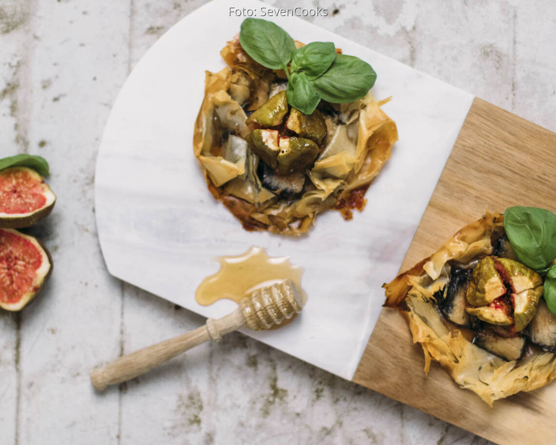 Zwei Asche Käse Tarteletts auf einem Brett mit Honig und Feigen