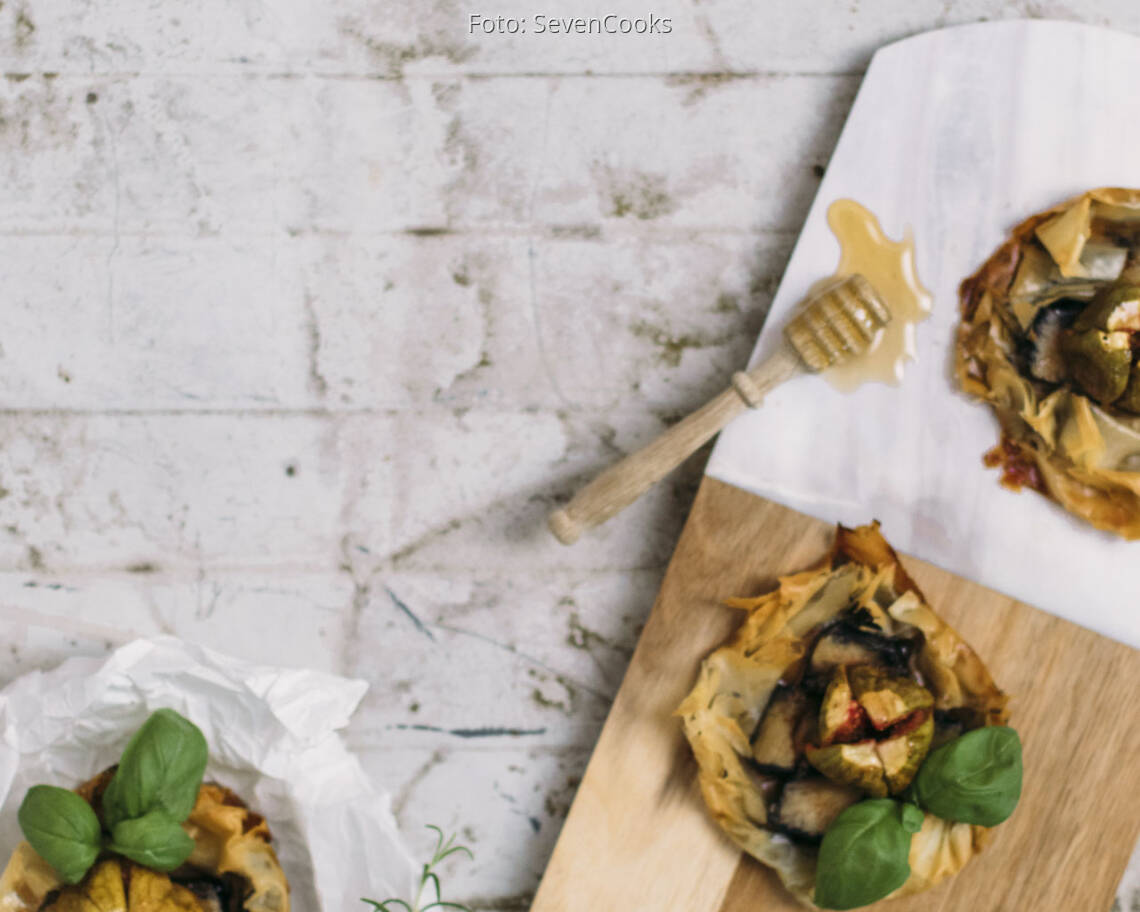 Zwei Asche Käse Tarteletts auf einem Brett mit Honig und Feigen