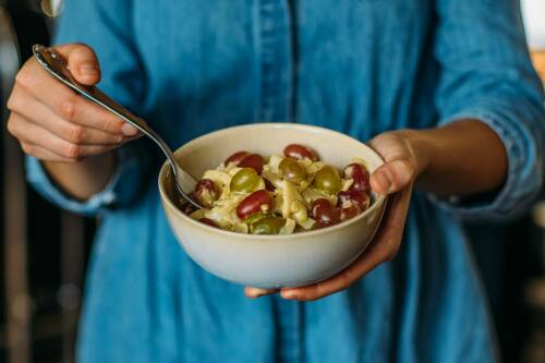 Fenchelsalat in Schüssel und Händen vor blauem Kleid.