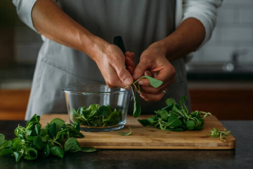 Fledsalat putzen in Schüssel mit Händen.