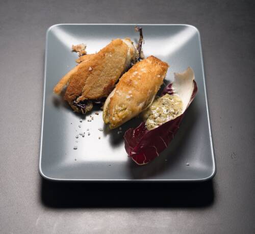 Frittierter Radicchio mit Chicorée vor dunklem Hintergrund.