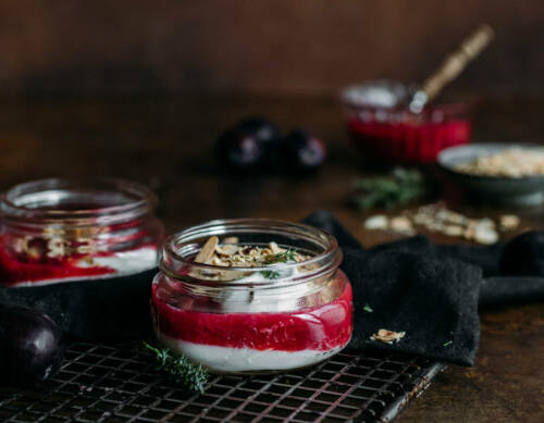 Fruchtiger Frühstücksjoghurt mit Zwetschgenkompott vor dunklem Hintergrund.