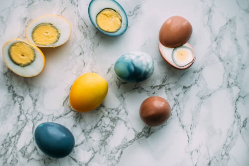 Gelbe, blaue und rote Ostereier ohne Schale auf Marmor