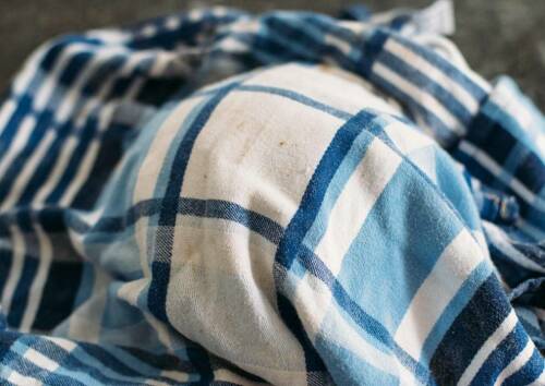 Zu sehen ist ein Geschirrtuch unter dem sich ein Brotteig befindet, von oben fotografiert.