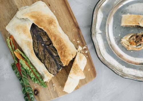 Festlicher Blätterteig-Strudel mit Gemüsefüllung auf einem Holzbrett von oben fotografiert.
