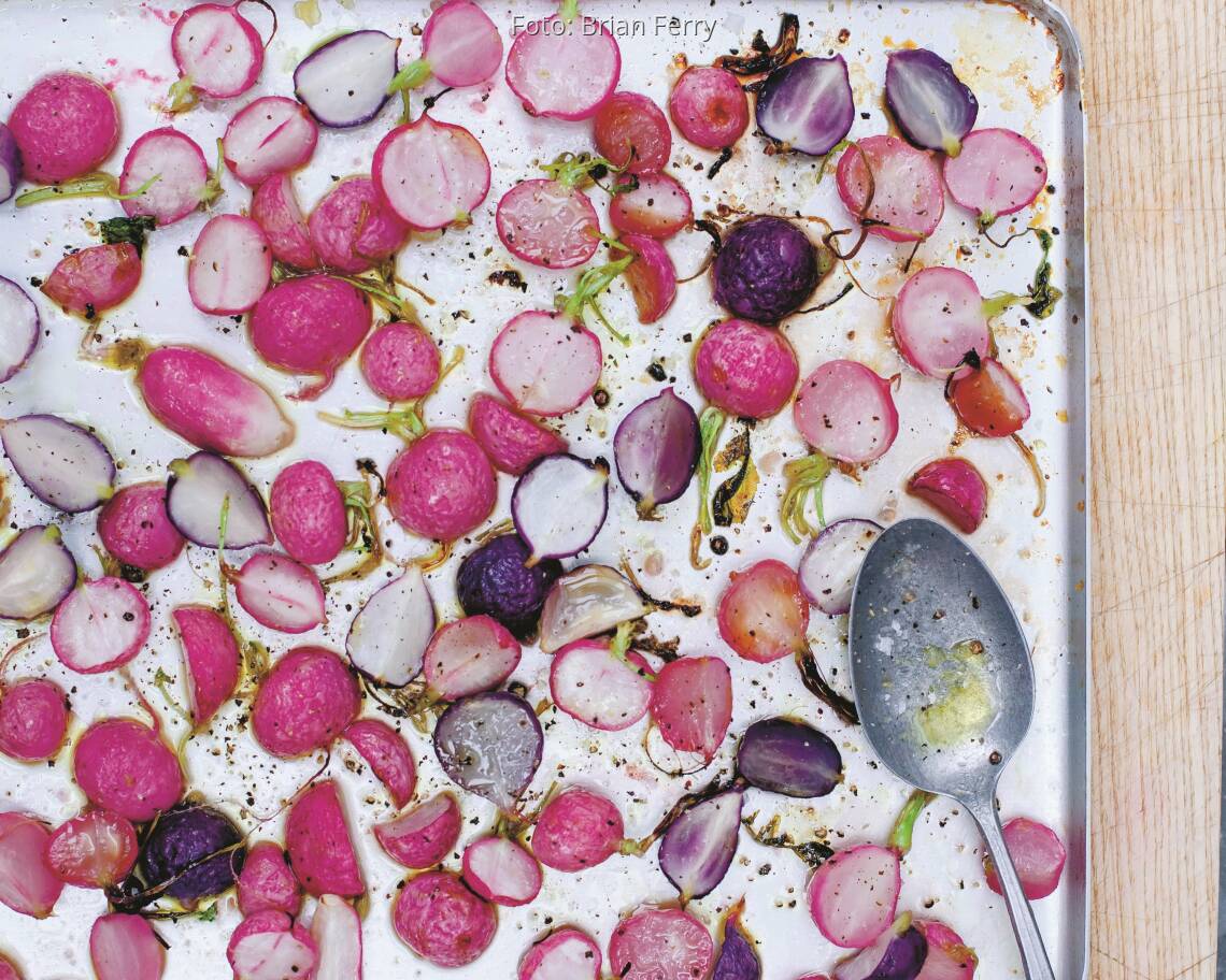 Aufgeschnittene Radieschen auf einem Backblech mit Gewürzen und Olivenöl