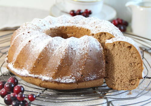 Klassischer Gewürzkuchen mit Puderzucker bestäubt auf einem Gitter. Von vorne fotografiert.