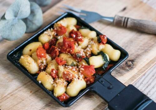 Raclette-Variante mit Gnocchi und getrockneten Tomaten im Pfännchen. Von oben fotografiert.