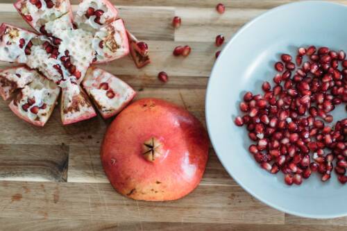 Schüssel mit Granatapfelkernen und eine leere Schale von oben