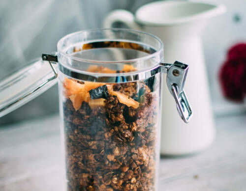 Granola Knuspermuesli in Glas vor hellem Hintergrund.