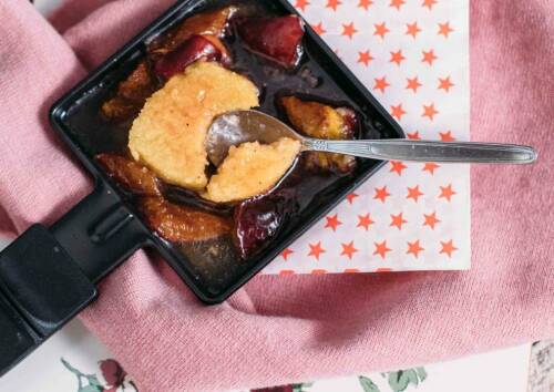 Leckeres Raclette-Pfännchen mit süßer Grießnocke und Zwetschgen von oben fotografiert.