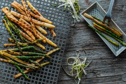 Grill Spargel  auf Gitter neben Schäler vor dunklem Hintergrund.