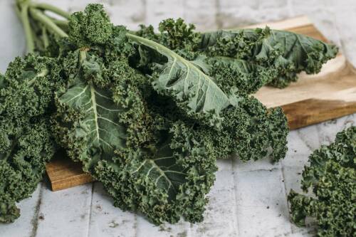 Grünkohlblätter auf einem Holzbrett.