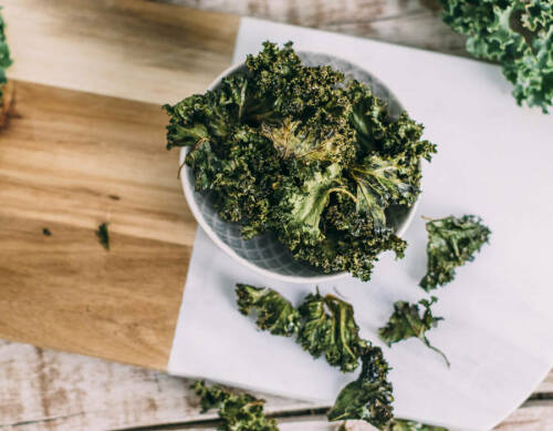 Grünkohl-Chips in Schüssel vor hellem Hintegrund.