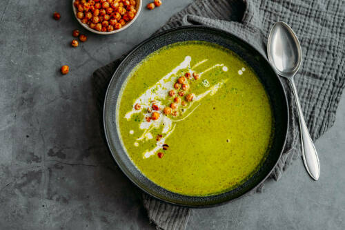 Selbsgemachte Suppe aus Grünkohl und Kokos in einem dunklen Teller.