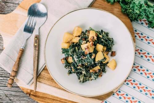 Modernes Grünkohlgericht mit Kartoffeln und Räuchertofu von oben fotografiert auf einem weißen Teller.