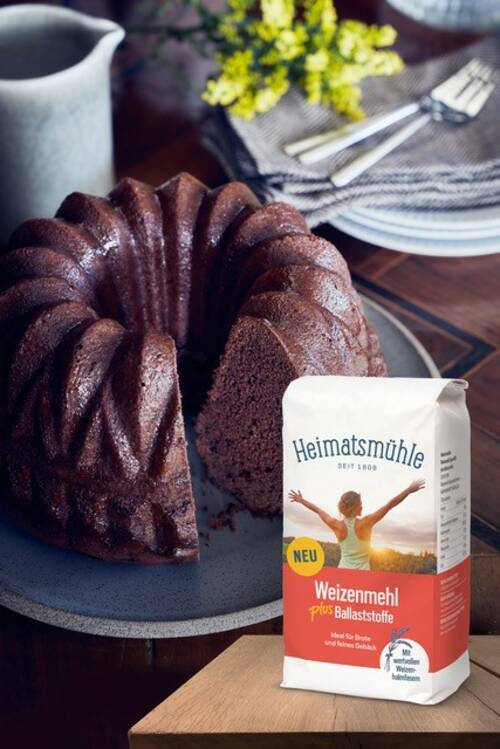 Selbstgebackener dunkler Guglhupf mit einer Mehlpackung "Weizenmehl plus Ballaststoffe" von Heimatsmühle.