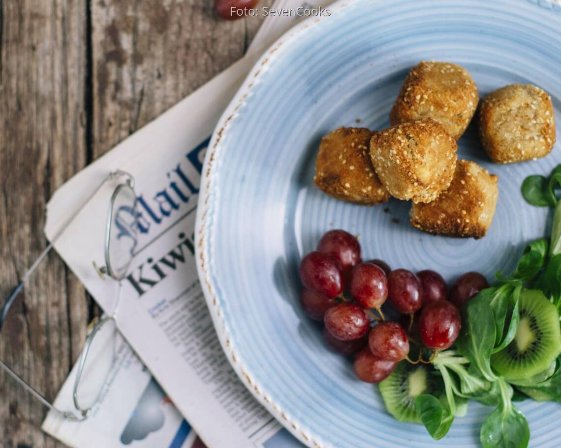 Käsekugeln mit Salat und Trauben auf einem Teller