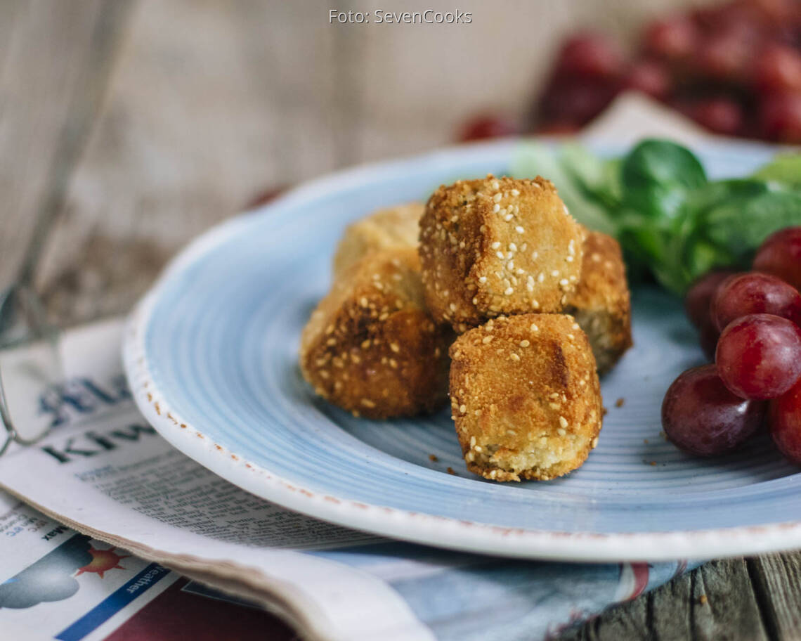 Käsekugeln mit Salat und Trauben auf einem Teller