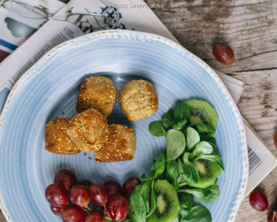 Käsekugeln mit Salat und Trauben auf einem Teller