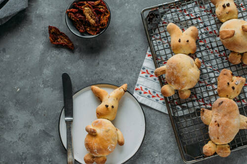 Hasenbrot auf Gitter und Teller neben getrockneten Tomaten vor hellem Hintergrund.