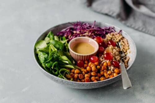 Bunte Bowl in einer Schüssel mit Rotkohl, Kcihererbsen, Bauchweizen und Feldsalat.